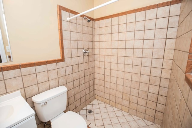 full bathroom with a tile shower, toilet, and vanity