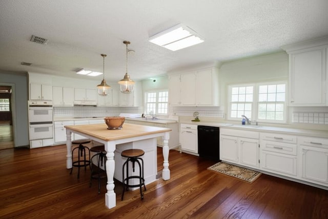 kitchen featuring dark wood-style flooring, white double oven, visible vents, black dishwasher, and white cabinetry