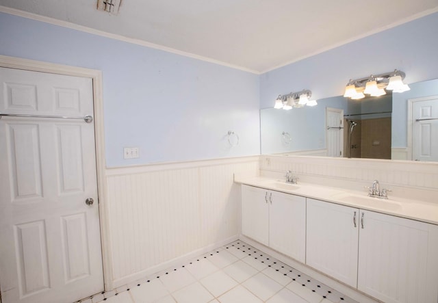 full bath with double vanity, a sink, walk in shower, and wainscoting