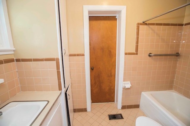 bathroom featuring vanity, tile walls, toilet, tile patterned floors, and wainscoting