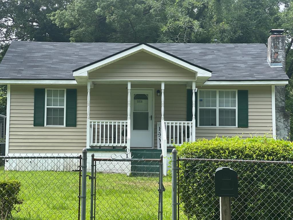 313 Felix St, Thomasville, GA 31792 - view of front facade featuring covered porch, a fenced front yard, a gate, and a chimney