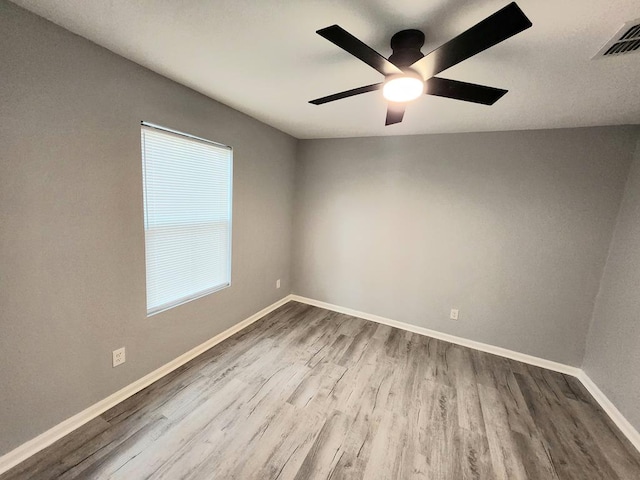 empty room with baseboards, visible vents, wood finished floors, and ceiling fan