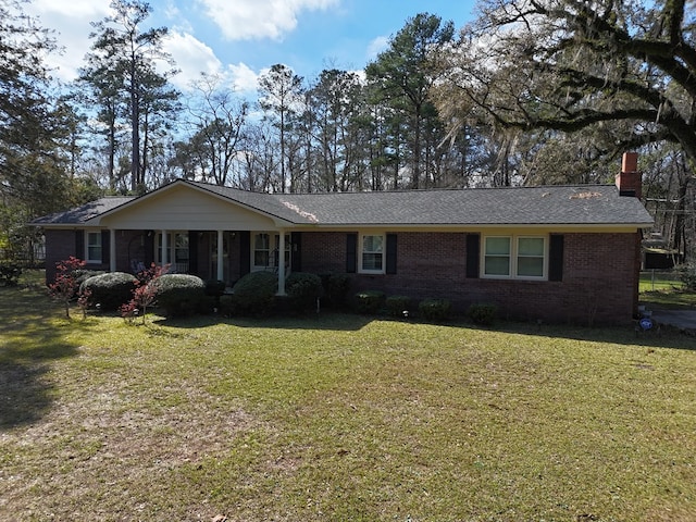 ranch-style house featuring brick siding, a chimney, and a front lawn