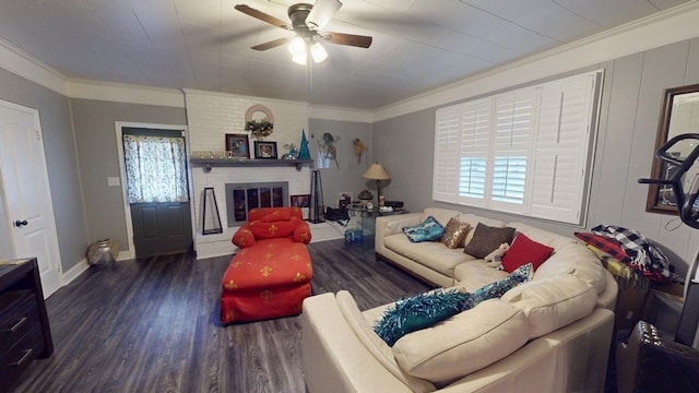 living room featuring dark wood-style floors, ornamental molding, a brick fireplace, ceiling fan, and baseboards