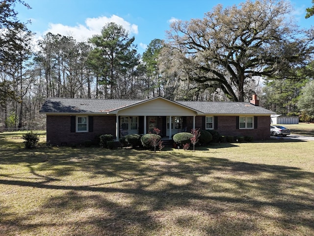 single story home with a front yard, covered porch, brick siding, and a chimney