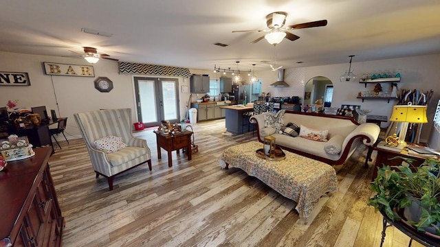 living room featuring arched walkways, visible vents, wood finished floors, and a ceiling fan