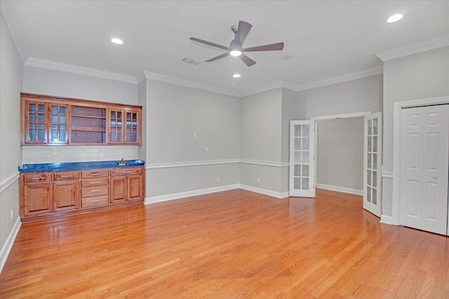 interior space featuring visible vents, ornamental molding, ceiling fan, french doors, and light wood-style flooring