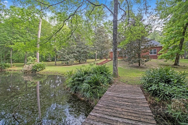 dock area with a lawn and a water view