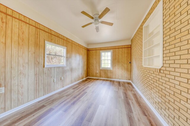 spare room with brick wall, ceiling fan, and light hardwood / wood-style flooring