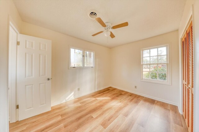 unfurnished bedroom featuring ceiling fan, a closet, and light hardwood / wood-style flooring