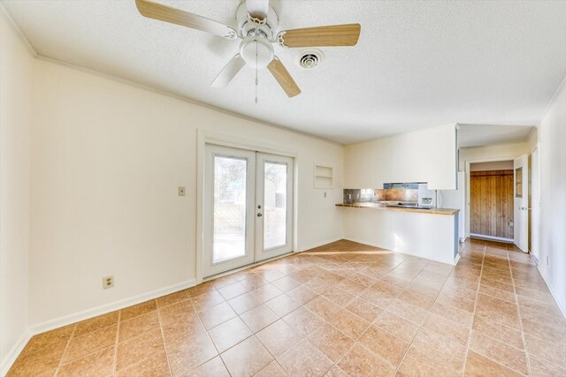 unfurnished living room featuring ceiling fan, light tile patterned floors, french doors, and a textured ceiling