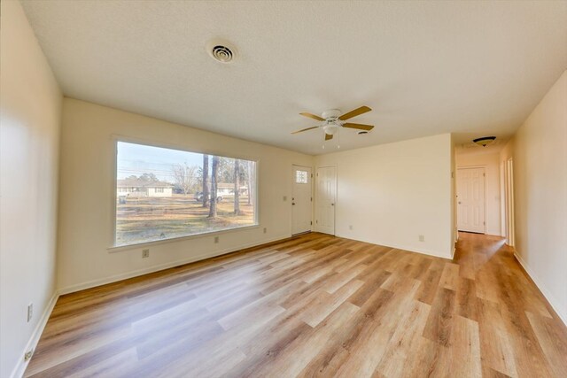 empty room featuring ceiling fan, light hardwood / wood-style floors, and a textured ceiling