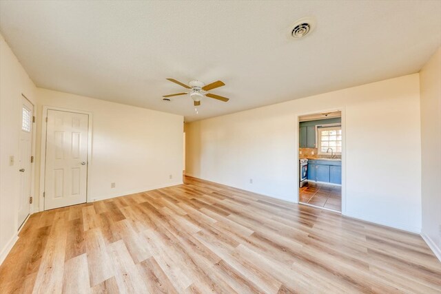 empty room featuring ceiling fan, light hardwood / wood-style floors, and sink