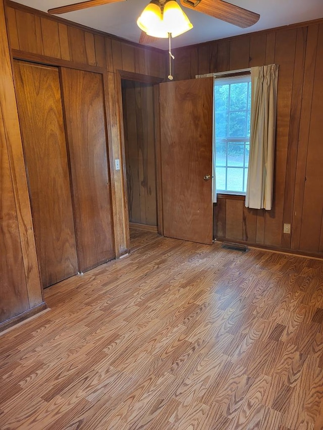208 Pine St, Quitman, GA 31643 - unfurnished bedroom featuring light wood finished floors, wooden walls, and a ceiling fan