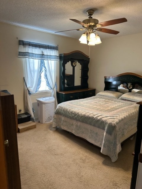 bedroom with ceiling fan, light carpet, and a textured ceiling