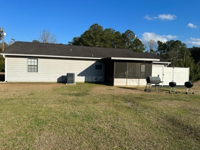 rear view of house featuring cooling unit, a sunroom, and a lawn