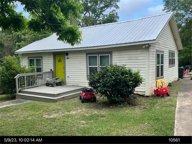 view of front of home featuring metal roof, a front lawn, and a wooden deck