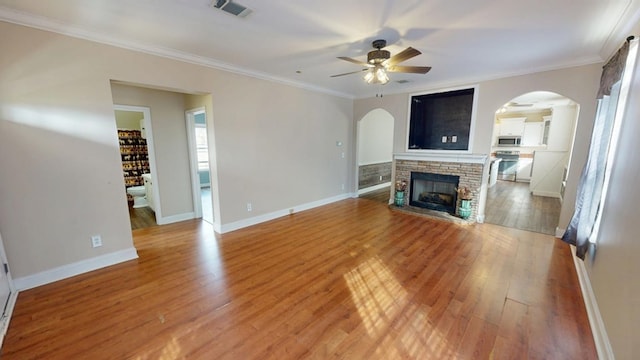 unfurnished living room featuring crown molding, a fireplace, light hardwood / wood-style floors, and ceiling fan