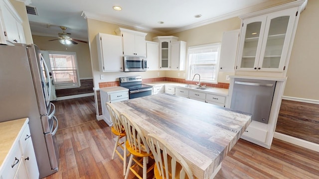 kitchen with sink, white cabinetry, a center island, light hardwood / wood-style flooring, and appliances with stainless steel finishes