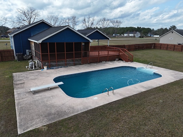 view of swimming pool with a diving board, a sunroom, a yard, cooling unit, and a patio