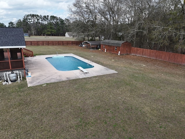 view of swimming pool with a diving board, a yard, a patio area, and a storage unit