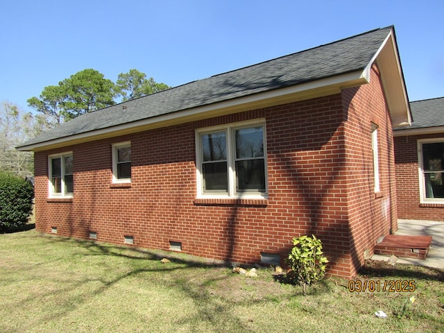 view of home's exterior featuring roof with shingles, brick siding, and crawl space