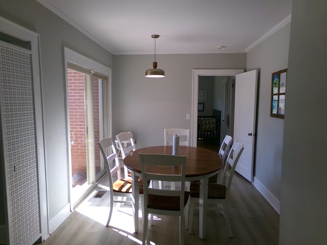 dining room featuring light wood-style floors, visible vents, ornamental molding, and baseboards