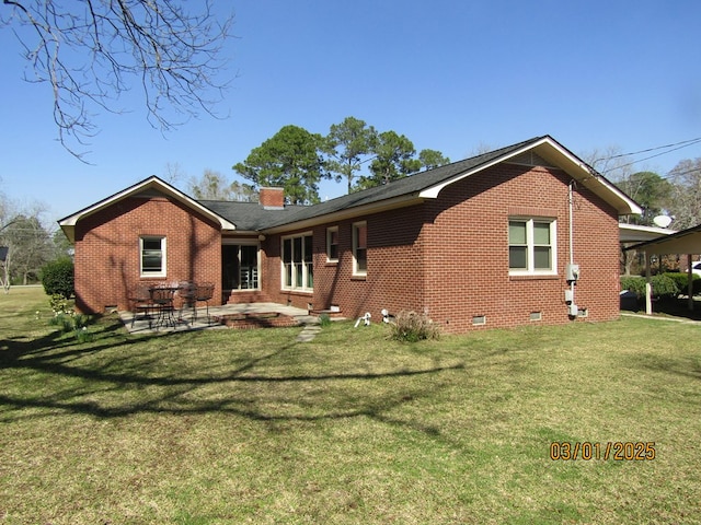 back of property with crawl space, a patio, a lawn, and brick siding