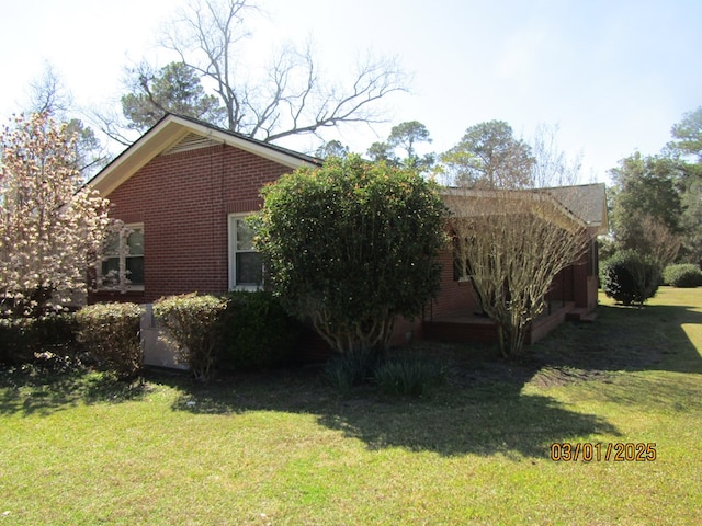 view of side of property with brick siding and a lawn