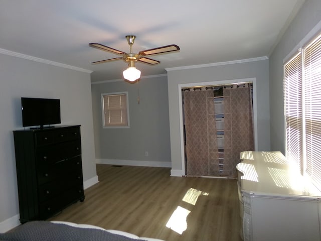 bedroom with light wood-style flooring, a ceiling fan, baseboards, a closet, and crown molding