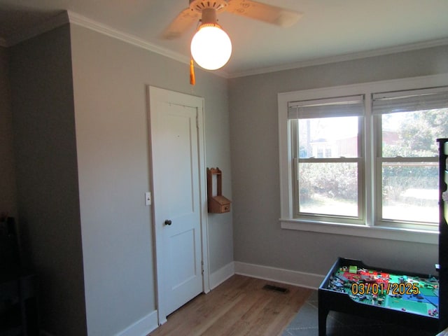 recreation room featuring ornamental molding, light wood finished floors, visible vents, and baseboards