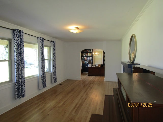 interior space with crown molding, arched walkways, and wood finished floors