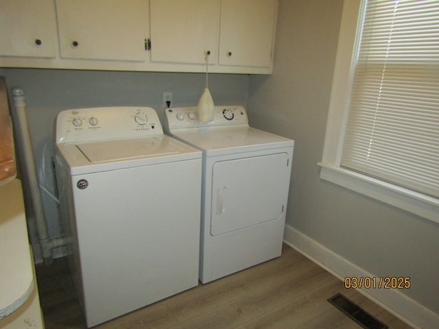 laundry area with light wood finished floors, cabinet space, baseboards, visible vents, and independent washer and dryer