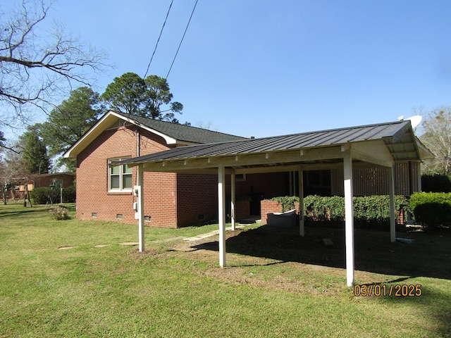 view of side of property featuring crawl space, brick siding, a yard, and a standing seam roof