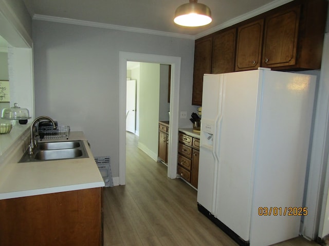 kitchen with crown molding, light wood-type flooring, white refrigerator with ice dispenser, and a sink