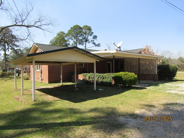 rear view of house with brick siding, a carport, and a yard