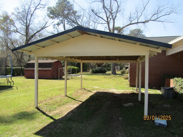 view of yard with an outbuilding, a storage shed, driveway, a carport, and a trampoline