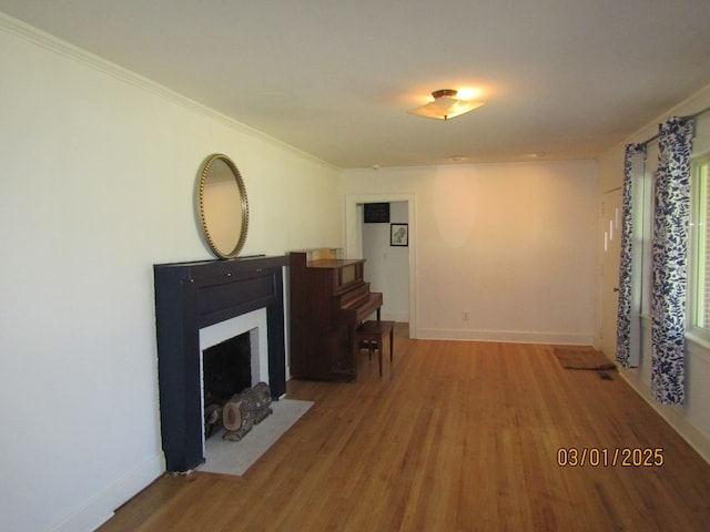 living area with a fireplace with flush hearth, baseboards, and wood finished floors