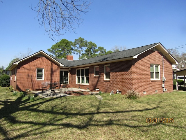 back of house with a lawn, a chimney, crawl space, a patio area, and brick siding