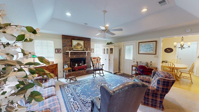 living room with visible vents, a brick fireplace, recessed lighting, a raised ceiling, and ceiling fan with notable chandelier