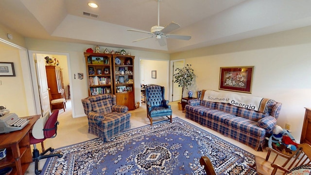 living room with visible vents, a ceiling fan, and a raised ceiling