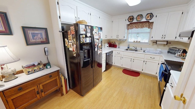kitchen featuring white cabinets, a sink, light wood-style flooring, range hood, and black appliances