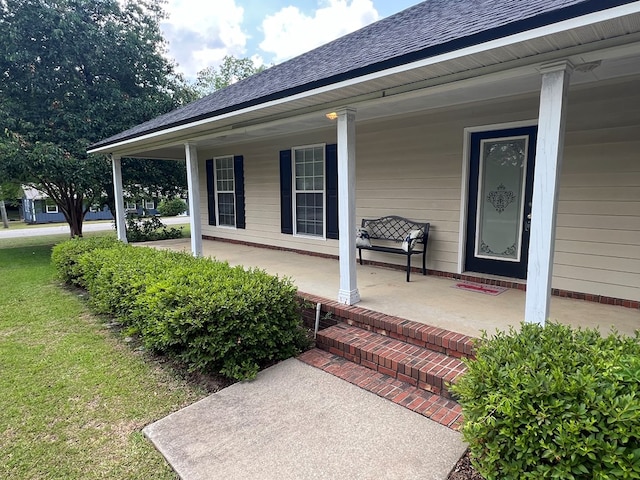 doorway to property with roof with shingles, a yard, and a porch