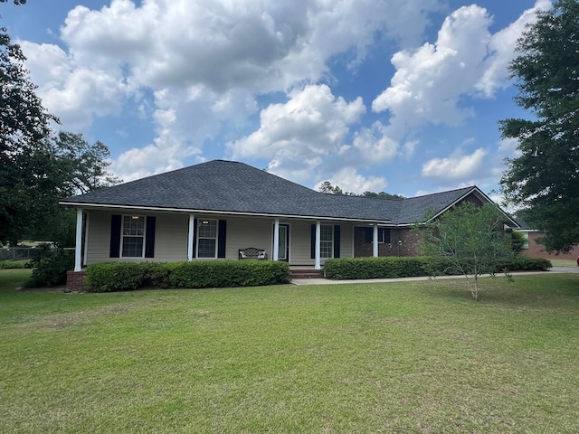 view of front of home with covered porch, a shingled roof, and a front lawn
