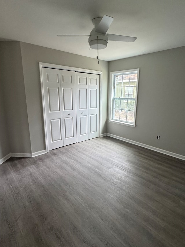 unfurnished bedroom with dark wood-style floors, a ceiling fan, baseboards, and a closet