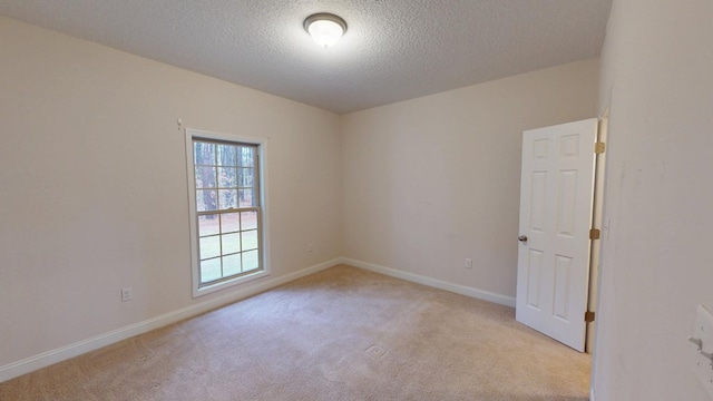 unfurnished room with baseboards, light carpet, and a textured ceiling