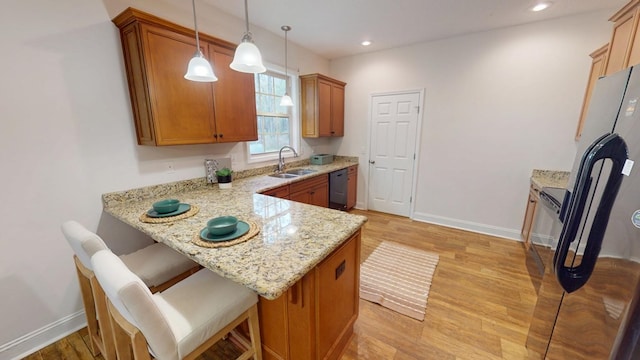 kitchen featuring a sink, light wood-type flooring, dishwasher, and a peninsula