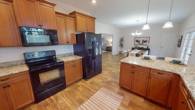 kitchen with pendant lighting, light wood-style floors, black appliances, and brown cabinetry