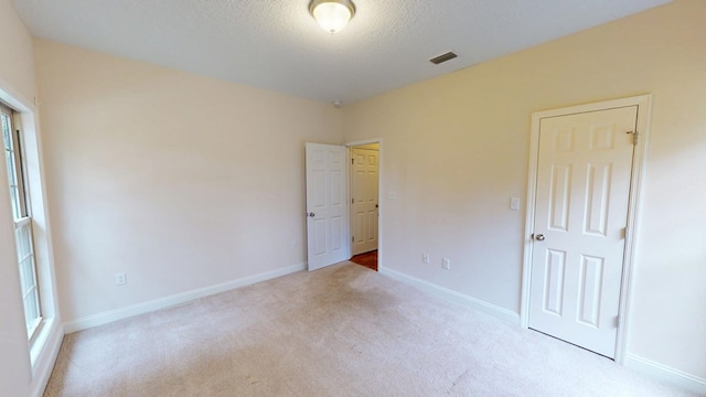 unfurnished bedroom with visible vents, baseboards, carpet, and a textured ceiling