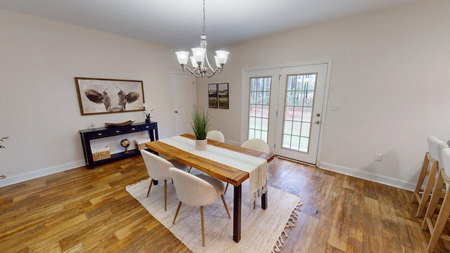 dining room with a notable chandelier, wood finished floors, and baseboards